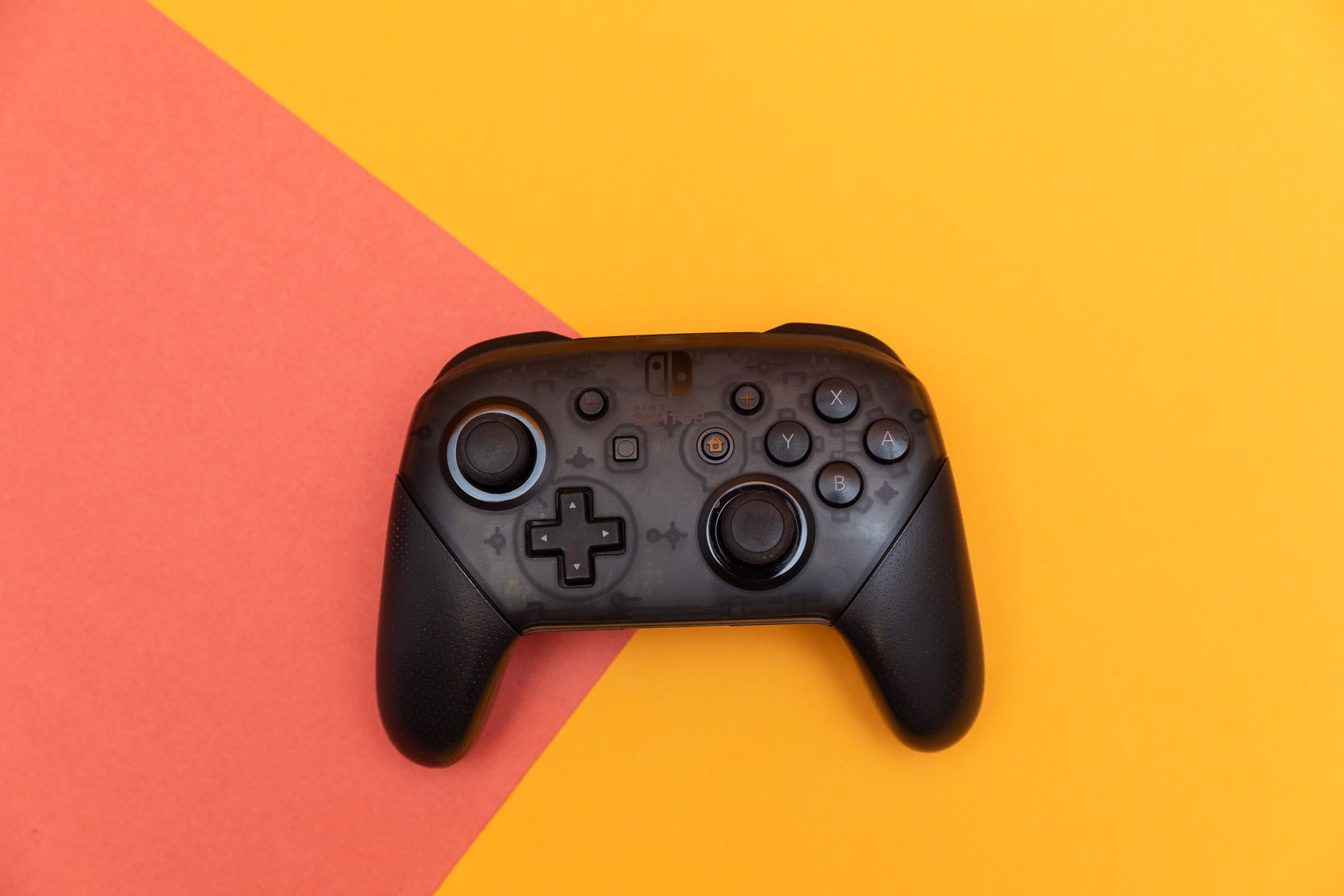 The Nintendo Switch Pro Controller sitting flat on a two-colored backdrop.